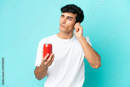 Young Argentinian man holding a refreshment isolated on blue background frustrated and covering ears