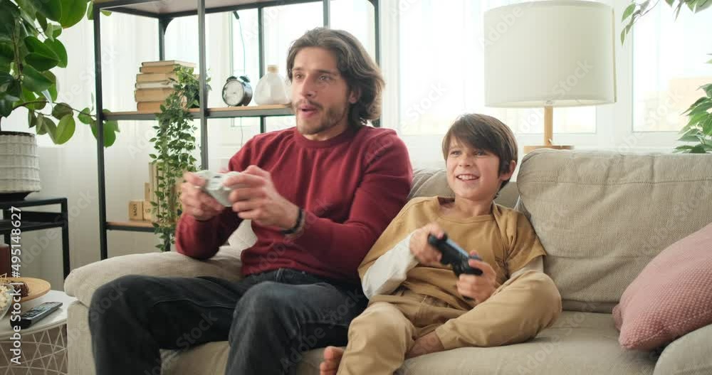 Enthusiastic father with son playing video game and celebrating win at home Enthusiastic father with son playing video game and celebrating win at home