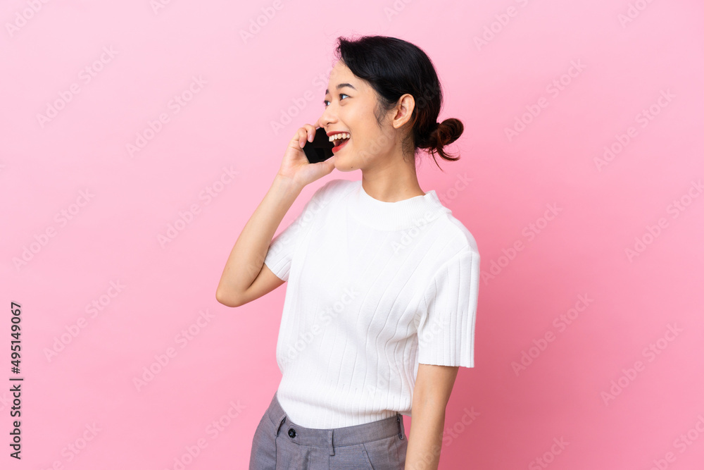 Young Vietnamese woman isolated on pink background keeping a conversation with the mobile phone Young Vietnamese woman isolated on pink background keeping a conversation with the mobile phone