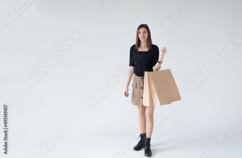 A cheerful girl in a black T-shirt and with brown empty paper bags on a white background.