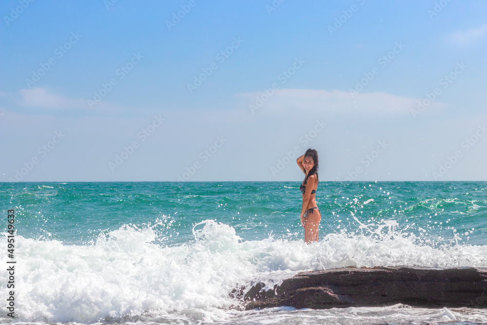 A beautiful emotional model girl splashes in the sea and laughs. Water splashes. Rest near the sea. The sea season.