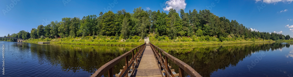 view of the pontoon pedestrian bridge across the Gauja river, Ogre, Latvia.. Reflection of the forest in the water of the river. panoramic photo