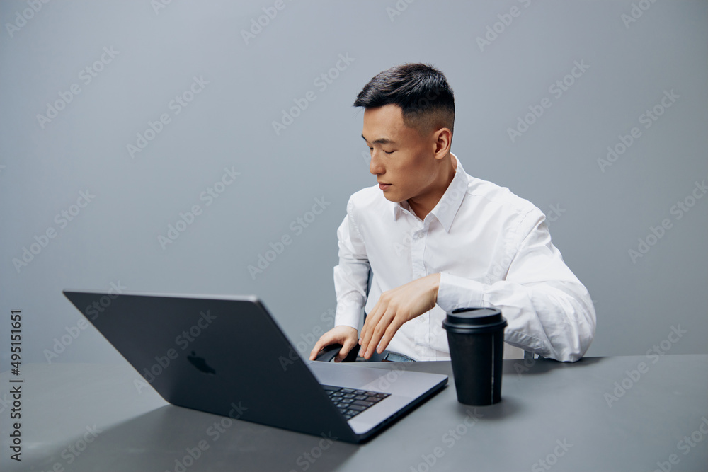 manager in white shirts glass of coffee sits in front of a laptop office Gray background manager in white shirts glass of coffee sits in front of a laptop office Gray background