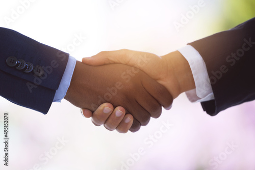 Coin and cash for poise and panache. Shot of two unrecognizable businessmen shaking hands against a blurry background.