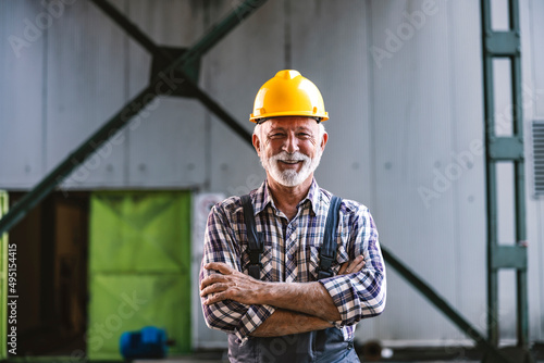 A proud smiling senior worker is standing in the factory and looking at the camera. photo