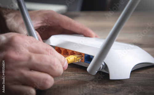 Obraz na płótnie Man plugging internet cable into wifi router.