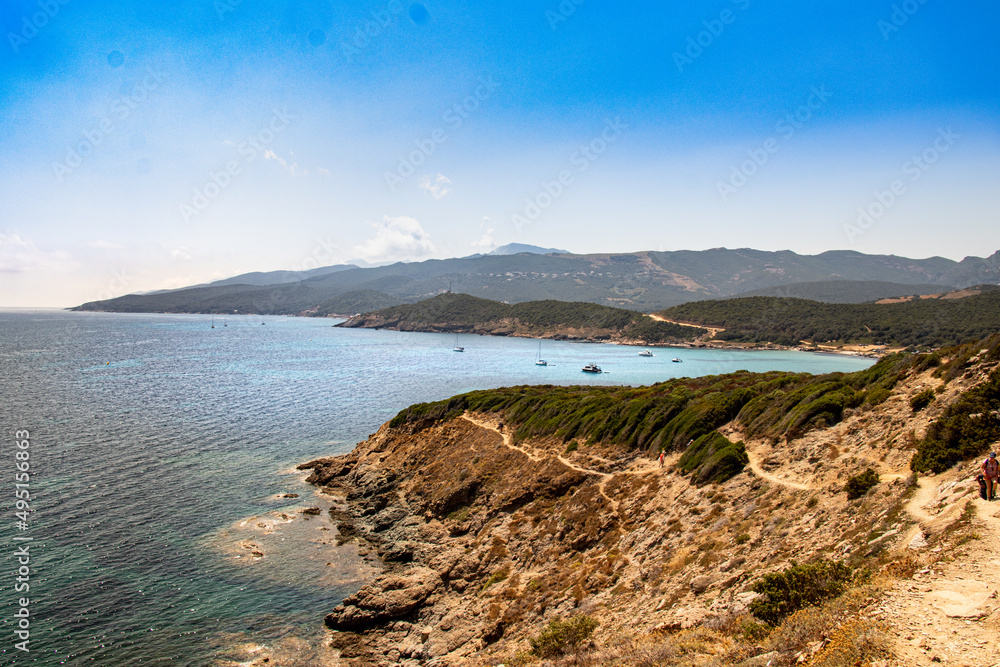 Obraz premium Corsican scrubland overhanging the coasts and beaches of Corsica near the Mediterranean Sea where several boats have dropped anchor