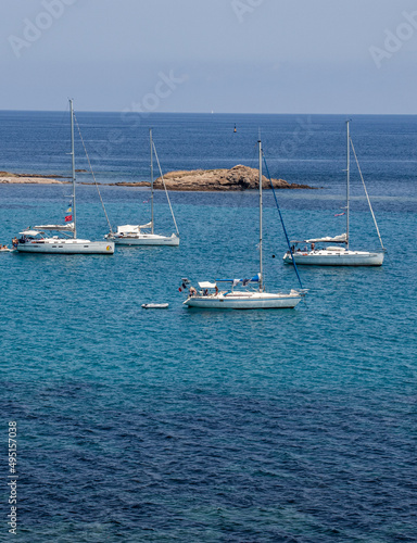 Sailing boats having dropped anchor near the coast of Corsica in a translucent, clear and calm Mediterranean sea © Julien