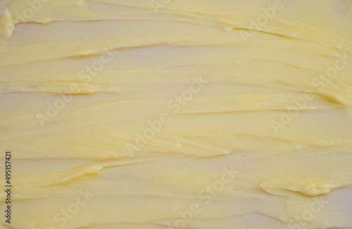 Cosmetic products creamy yellow stain texture on pink background. Texture of natural cosmetics, hair mask, cream, scrub