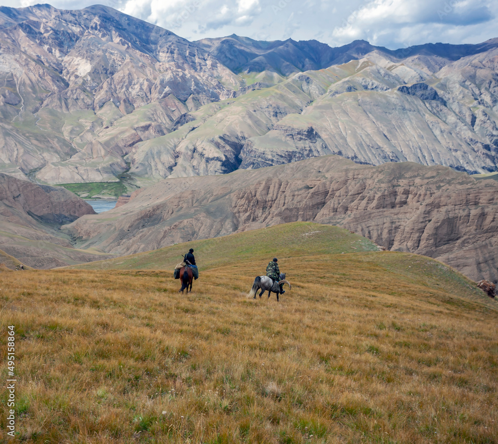 Riders on horseback with weapons descend the mountain slope.