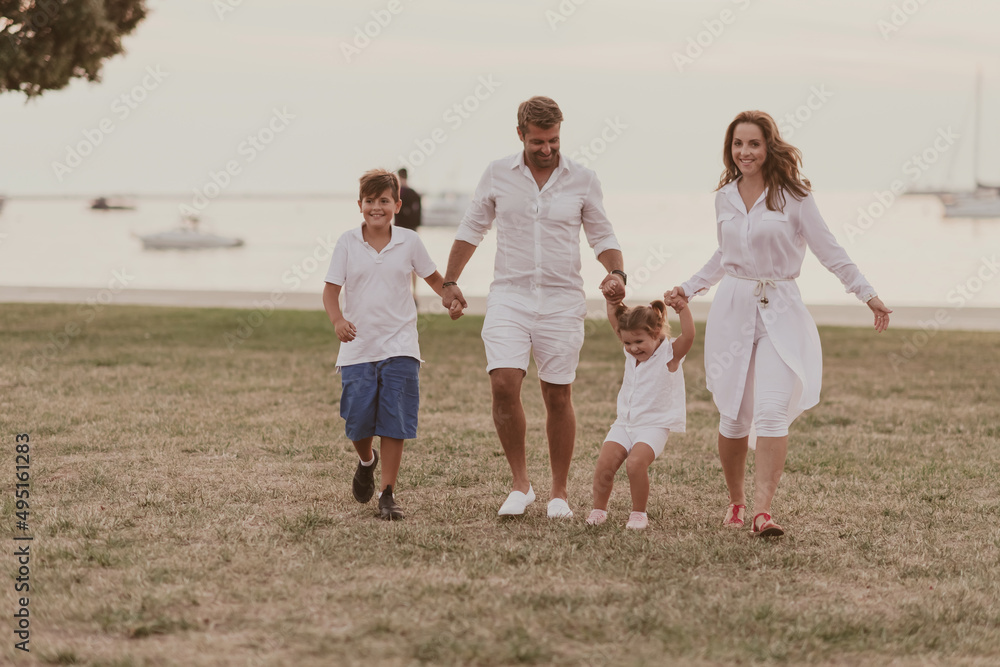 Senior couple in casual clothes with their children, boy and girl enjoy the beach spending a vacation together. Family time . Selective focus Senior couple in casual clothes with their children, boy and girl enjoy the beach spending a vacation together. Family time . Selective focus