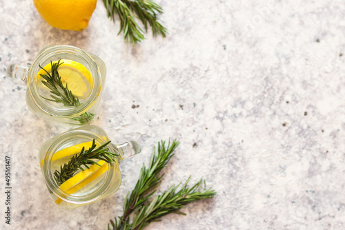 Top view of two jars of lemonade with ice, lemon and rosemary. Copy space, flat lay. Refreshing summer drinks. Selective focus