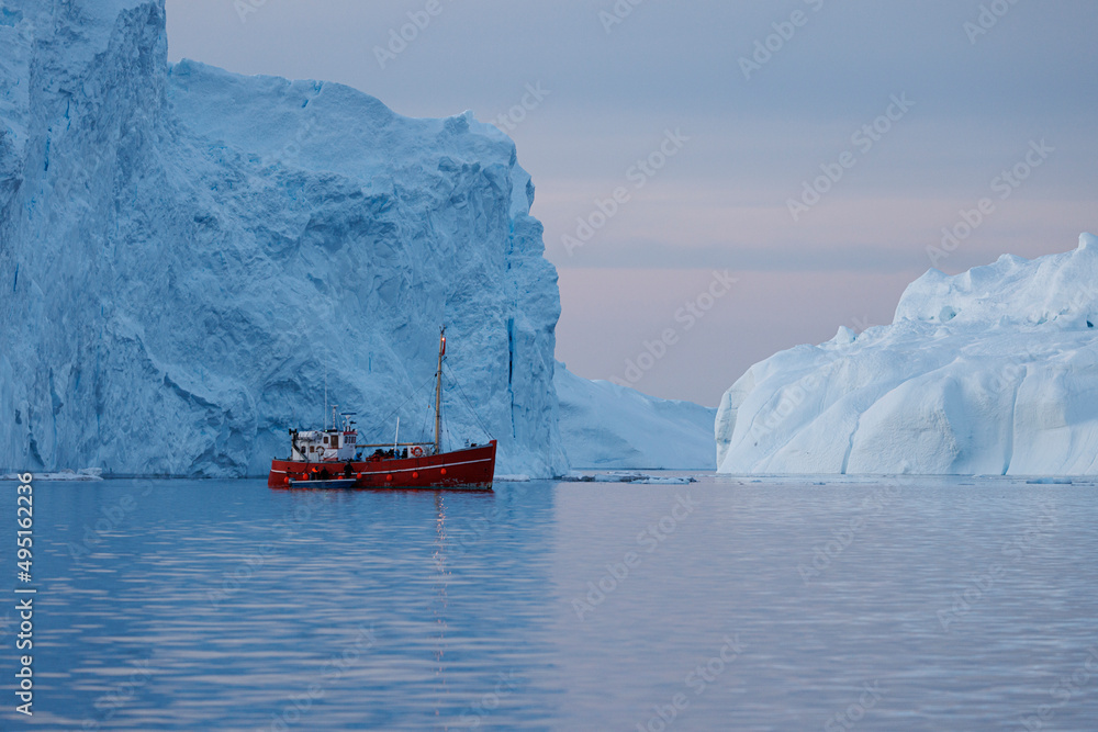 red ship in front of icebergs