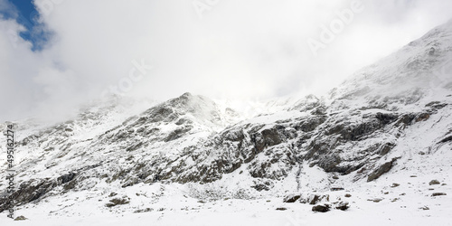 Panorama of a winter landscape of a mountainous area in foggy weather. Snow-covered valley and mountain peaks covered with snow. Location Carpathians of Romania, Transylvania.