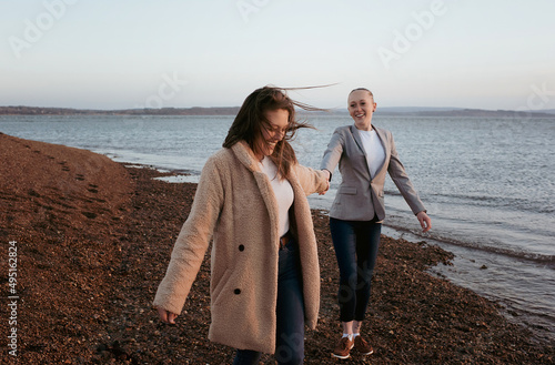 lesbian couple holding hands playfully at the beach photo