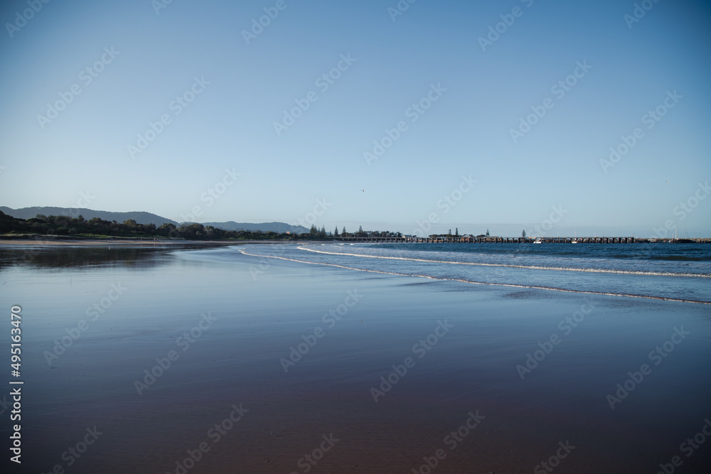 Waves rolling in on Coffs Harbour Beach with jetty in the distance, Australia