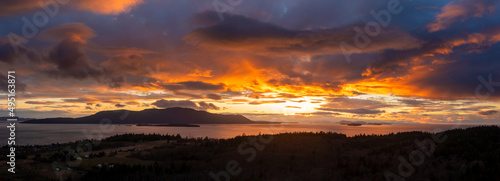 Aerial Panoramic View of Orcas Island During a Dramatic Sunset. Seen from neighboring Lummi island looking across Rosario Strait at the sun dropping below the dynamic cloudscape.