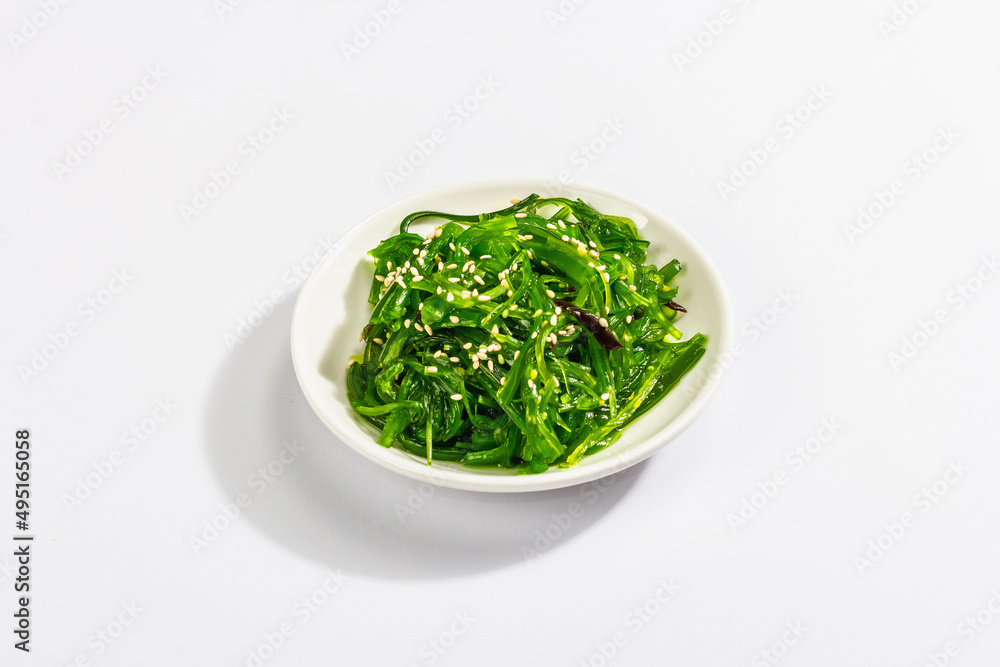Chuka Seaweed Salad with sesame seeds isolated on white background. Trendy hard light, dark shadow
