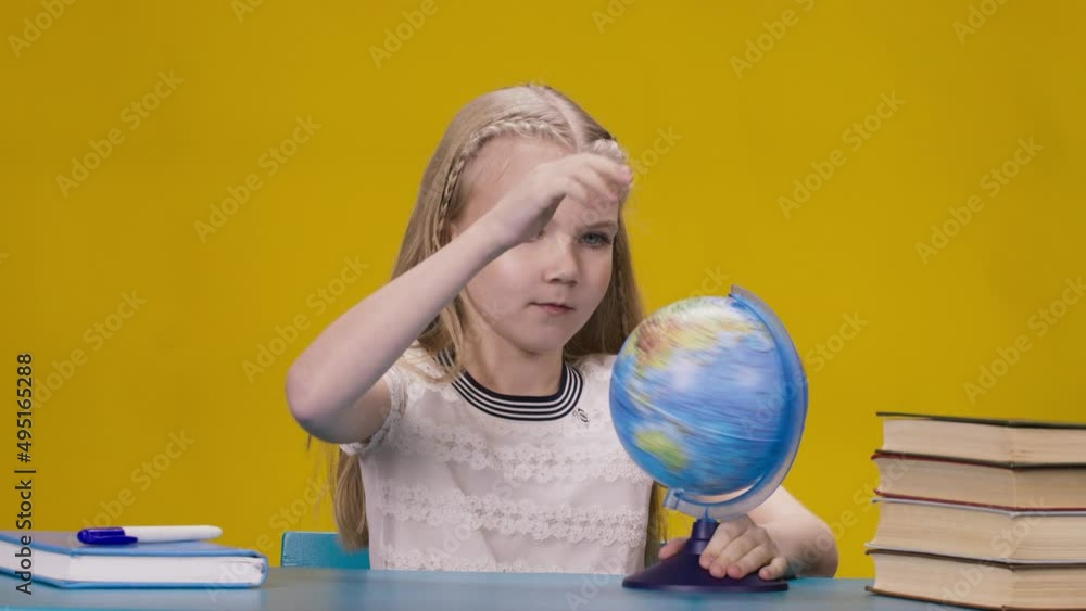 a little schoolgirl sitting at desk spinning globe a little schoolgirl sitting at desk spinning globe