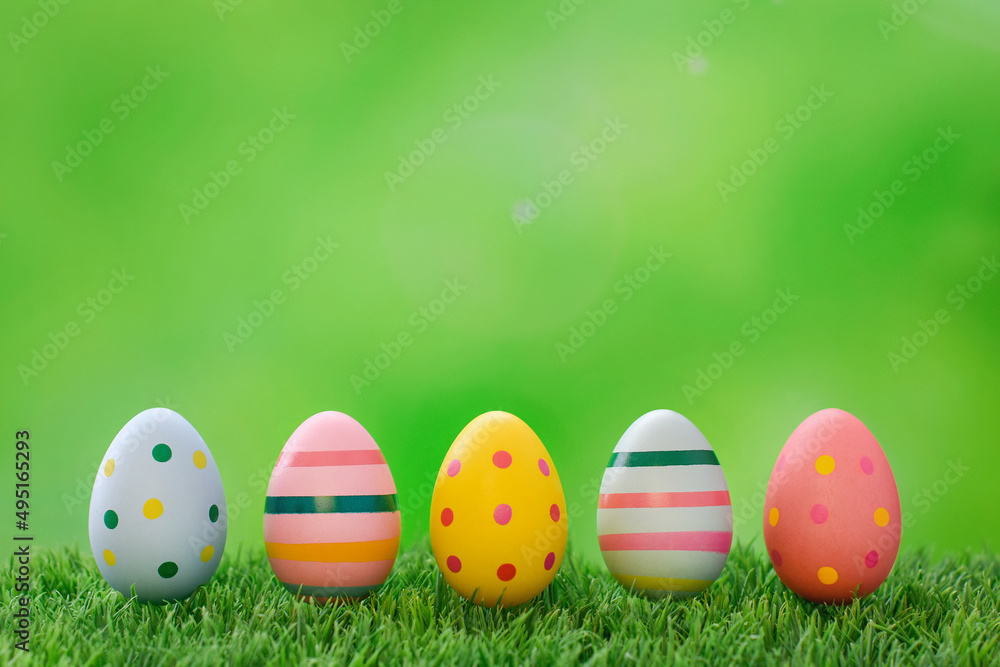Happy Easter Card. Old-fashioned colorful Easter eggs in a row on green grass. Striped and dotted vivid eggs in Retro style. Spring holiday backdrop with copy space.