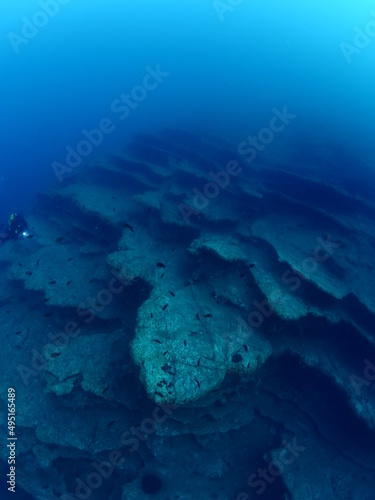 scuba divers around a reef underwater deep blue water big rocks  