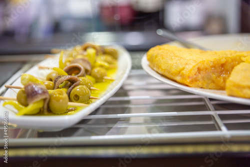 Skewers of potato omelette and olives on a bar counter