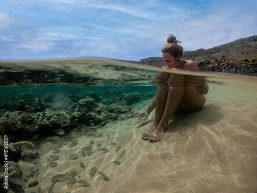 Blonde girl relaxing on water with fishes and marine life. Clear water at Lion Beach, Fernando de Noronha, Brazil photo