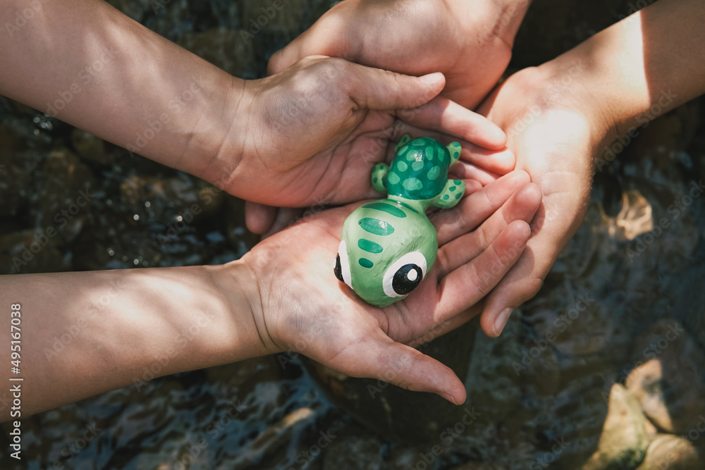 Hands holding turtle over natural rock pool, world turtle day, world, world ocean day, save wildlife, CSR concept Hands holding turtle over natural rock pool, world turtle day, world, world ocean day, save wildlife, CSR concept