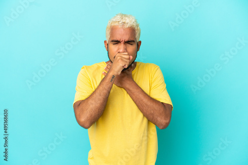 Young Colombian handsome man isolated on blue background coughing a lot