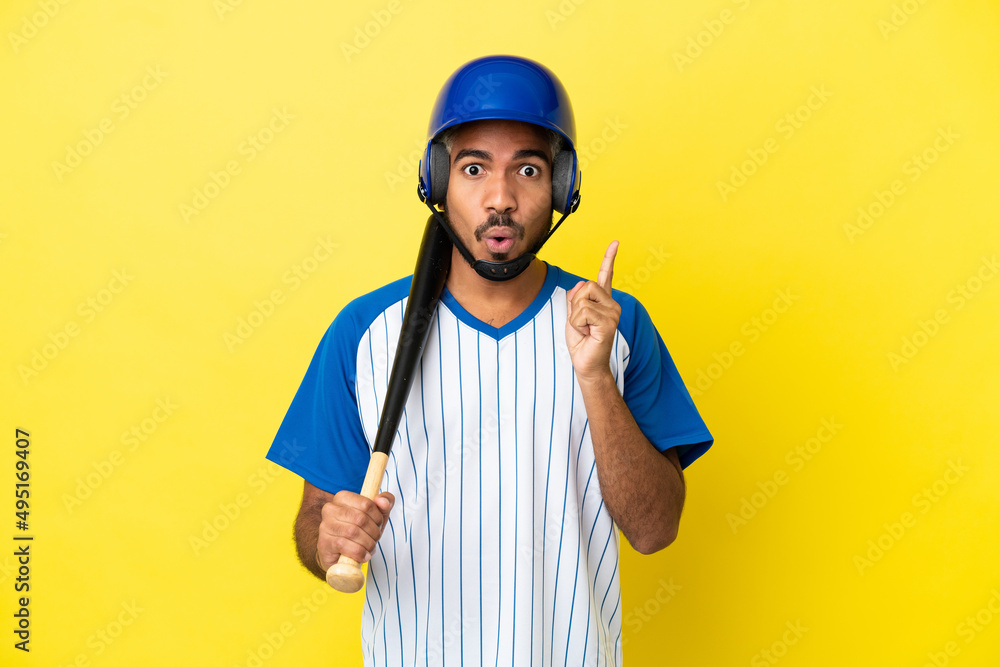 Young Colombian latin man playing baseball isolated on yellow background intending to realizes the solution while lifting a finger up