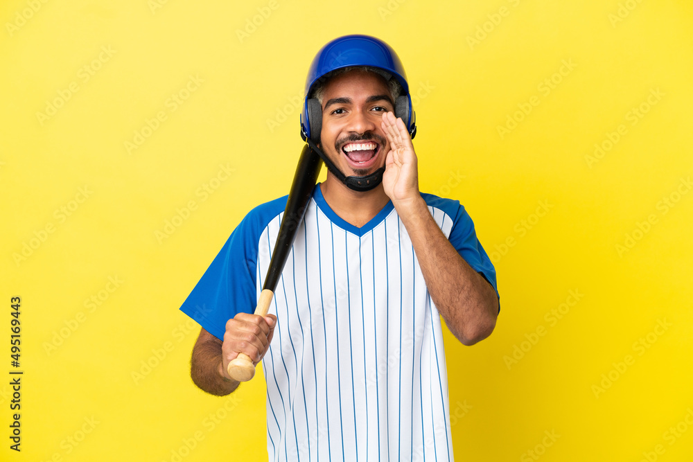 Young Colombian latin man playing baseball isolated on yellow background shouting with mouth wide open Young Colombian latin man playing baseball isolated on yellow background shouting with mouth wide open