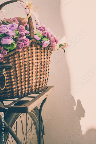 Artificial rose flower in basket on vintage bicycle. Vintage retro color tone.