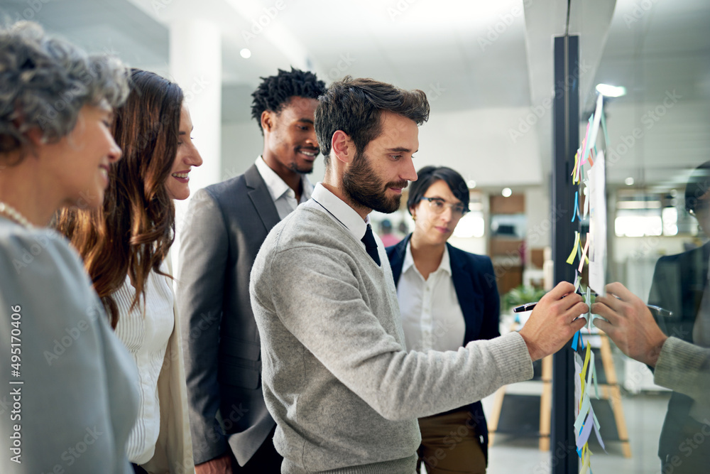 Obraz premium Heading up the planning committee. Shot of a group of businesspeople brainstorming on a glass wall in an office.