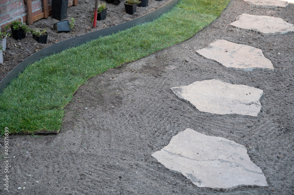 Making of natural green lawn in garden with rolls of green grass, garden works in spring Making of natural green lawn in garden with rolls of green grass, garden works in spring