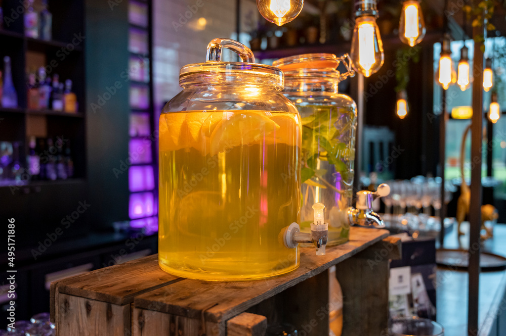 Big glass glass jar with tap filled with fresh healthy lemon lemonade drink served in bar for party Big glass glass jar with tap filled with fresh healthy lemon lemonade drink served in bar for party