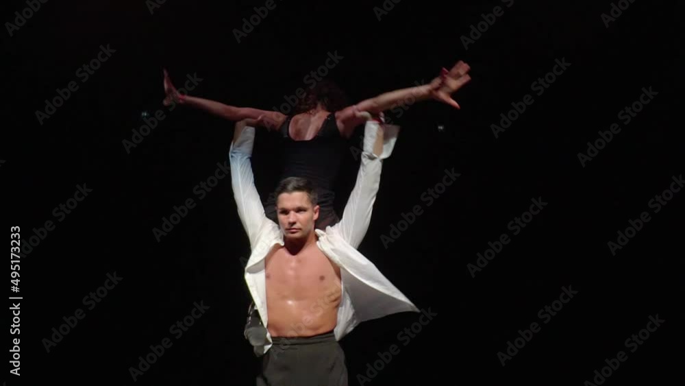 Close-up of male dancer taking woman from flip upside down,lifting her into dance support on shoulders from behind,rotating in beautiful pose.Slightly accelerated video of dancers pair on dark stage Close-up of male dancer taking woman from flip upside down,lifting her into dance support on shoulders from behind,rotating in beautiful pose.Slightly accelerated video of dancers pair on dark stage