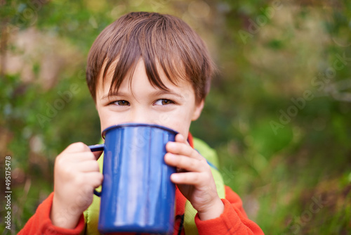 Preparing for an energetic days camping. Shot of a adorable little boy drinking from a mug while on a camping trip.