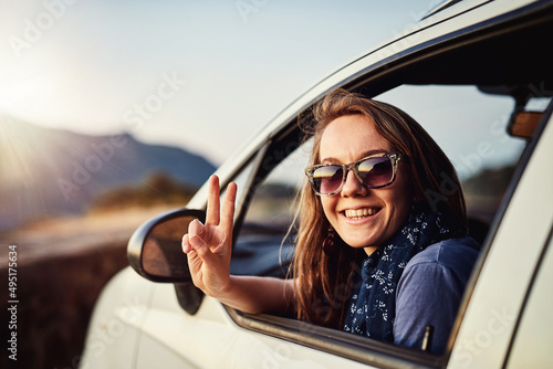 Take it easy. Portrait of a young woman showing a piece sign while sitting in her car. photo