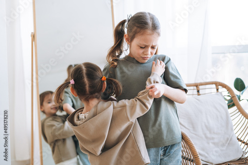 Little girls sisters have fight near mirror in children room at the home