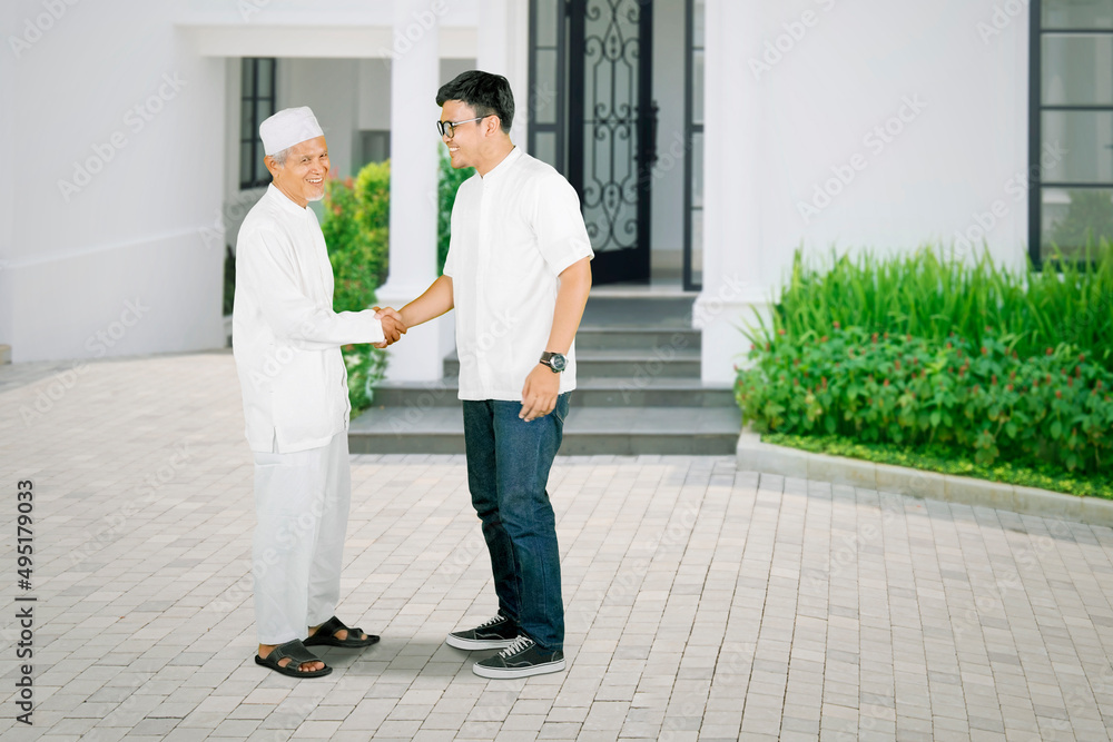 Fototapeta premium Elderly man handshaking with son in front of house