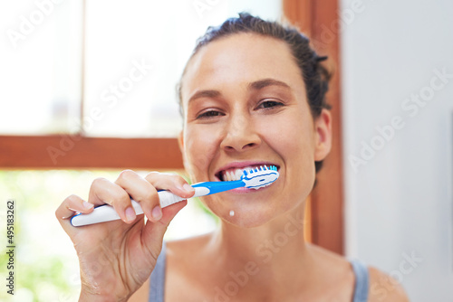 Dental hygiene is extremely important. Portrait of an attractive young woman brushing her teeth at home.
