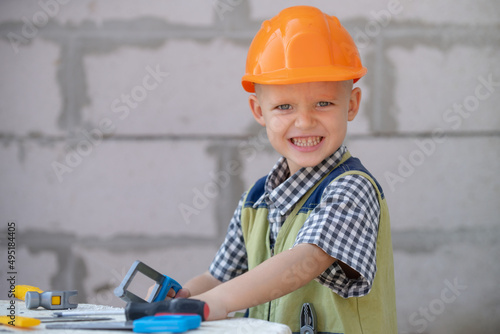 Child in building helmet, hard hat. Repair home. Child dressed as a workman builder. Portrait little builder in hardhats. Little builder in helmet.