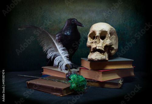 Books a human skull, a raven and a green carnation. photo