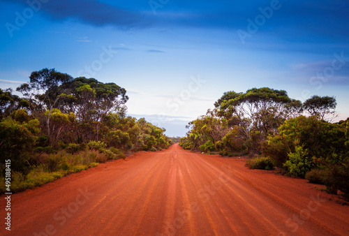 Empty open outback road in Western Australia. Straight single lane dirt road stretching into the distance. Desert scene, Endless travel and adventure.