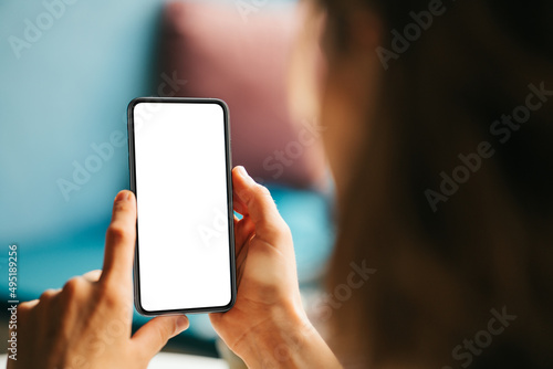 Woman in cafe holding blank white phone. Mockup empty background
