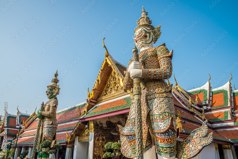 Fototapeta premium The two giant statue in Wat Pra Kaew temple, The Grand Palace, blue sky, Thailand. Asia travel business concept.