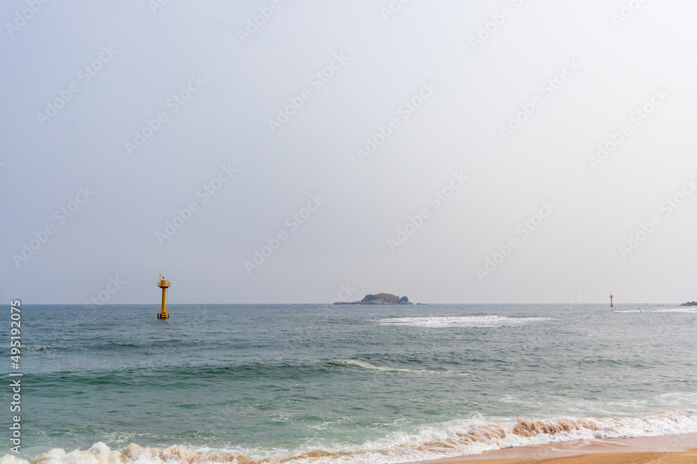 Cloudy day, sea, yellow lighthouse.
