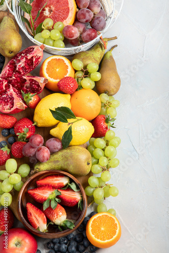 Assortment of colorful ripe tropical fruits on light gray background.