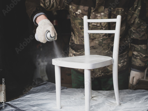 A man repairs old furniture.paints a children's chair with spray paint. handmade concept photo