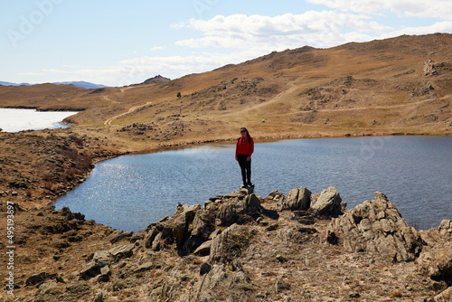 Lake Baikal, Olkhon Island in the spring. A girl looks at Lake Nuku-Noor or Lake Heart. Traveling alone. 